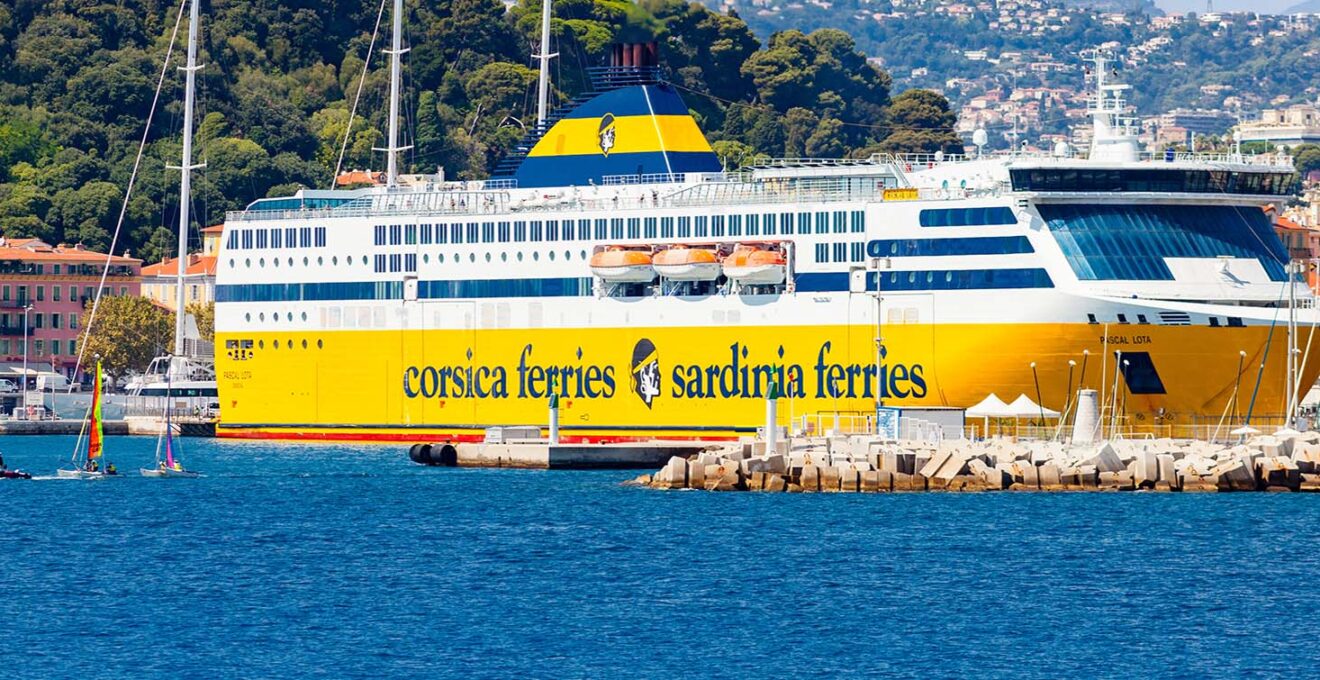 ferry Corsica and Sardinia yellow ferry boat docked in the harbour, city buildings on hills in background, French Riviera of Mediterranean Sea