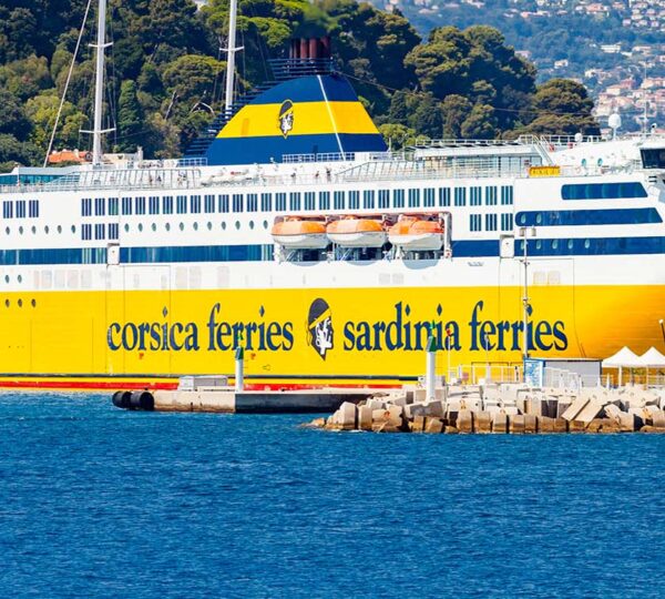 ferry Corsica and Sardinia yellow ferry boat docked in the harbour, city buildings on hills in background, French Riviera of Mediterranean Sea